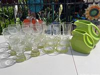 Set of glassware and two chartreuse Fiesta Ware pitchers displayed outdoors