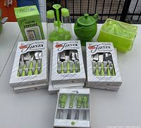 Photo showing boxed Fiesta Accessories flatware sets with chartreuse handles, glass cruet set, ceramic pitcher bank and plastic napkin dispenser in chartreuse green.
