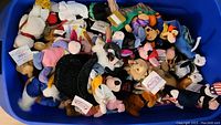Blue plastic bin labeled 'Disney Beanies' containing an assortment of Disney character bean bag plush toys including Tigger, Seven Dwarfs, Donald Duck, Goofy, Mickey Mouse, some with tags attached