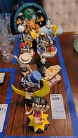Collection of nine Betty Boop figurines in various costumes and poses arranged on a table with lot identification card visible.