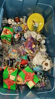 Photo of a plastic bin full of assorted fast food kids toys in original packaging and loose.