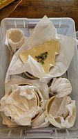 Plastic storage bin with wrapped ceramic dishes including tree-shaped platter and stacked plates.