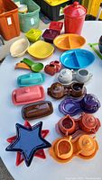 Overview of Fiesta Ware pieces showing colorful serving and dinnerware including canisters, divided dishes, butter dishes, and spoon rests in various colors.