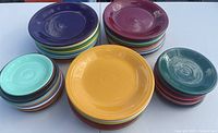 Top-down view of stacks of colorful Fiesta Ware plates showing variety of colors including mustard yellow, purple, green, and teal.
