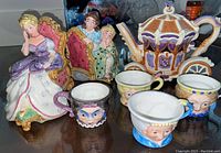 Overall view of all porcelain figurines and Cinderella tea set including teapot and character teacups.
