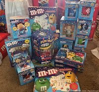 Wide view showing large assortment of M&M collectibles including puzzle, plush radios, dispensers, and character toys in colorful official packaging.