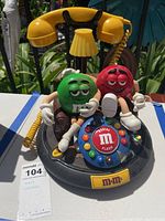 Front angle showing Red and Green M&M figurines seated around the rotary dial with yellow handset on stand