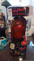 Front view showing Freddy Krueger figure in original windowed box, box has wear and creases, figure visible inside.