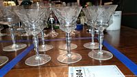 Front angle view of six etched crystal stemware glasses showing floral etching and elegant stems.