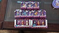 Photo of all nine boxed Winnie the Pooh collectible figures by Mattel arranged on glass table, showing packaging and number of figures