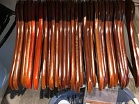 Close-up image of polished wooden hangers with dark finish hanging on a rod