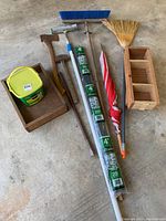 Full lot laid out on concrete floor including bucket of Miracle-Gro, plant stakes, broom, axe, mallet, wooden shelving, umbrella and wooden tray.