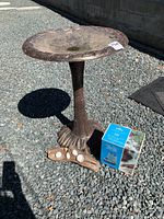 Full view of bird bath and additional items on gravel ground in daylight.