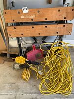 Full view of work bench, cords, mallet, dustpan, and work lights on floor