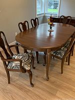 Full view of the solid cherry wood dining table with six chairs, showing polished oval tabletop and patterned seats.
