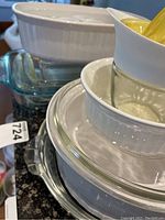 Stacked white Corning Ware ceramic dish with glass and lemon squeezer on top, showing clean condition.