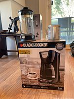 Black & Decker 12-cup programmable coffee maker in original box, French press and coffee cup seen beside it.