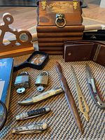 Overall overview of collection, showing wooden box, anchor clock, wallets, locks with keys, folding knives, letter opener-like utensil, magnifying glass