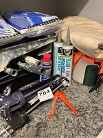 Shot of caulking guns, tubes of DAP Alex Plus caulk, WD-40 can, heavy drop cloth and orange strapping on counter