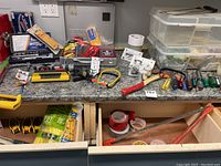 Workbench top with assorted hand tools, tape rolls, and plastic organizer boxes