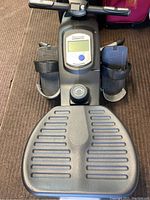 Top view showing foot pedals, textured footrest, digital monitor with button and the base of the rowing machine.