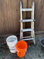 Full view of the extendable aluminum ladder with the three plastic buckets beside it, showing the overall lot contents.