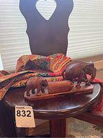 Wooden elephants on wooden surface with batik fabric and heart-back chair in the background