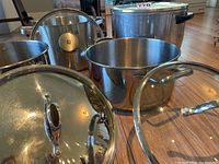 Photo showing four pots together: two Lagostina stainless steel pots, one Zwilling stainless steel pot with logo, and one large aluminum corncob-pattern pot.