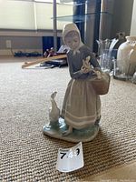 Front and angle view of the Lladró shepherdess figurine with ducks and goose, showing the detailed figure and basket with ducklings.