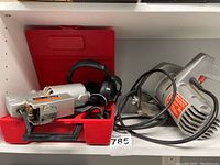 Photo of Black & Decker circular saw and Skil jigsaw with red carrying case and headphones on shelf.