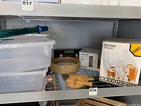 Shelf with three clear plastic storage containers with lids (one lid missing), boxed sets of glasses, a woven basket and bamboo tapas boards