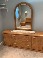 Full view of the wood-finish dresser and large arched matching mirror resting on top, showing the overall style and condition.