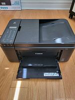 Front view of black Canon Pixma printer showing paper output tray and control panel.