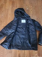 Inside view of a black winter jacket with hood showing lining and label