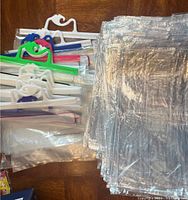 Clear plastic storage bags stacked in a pile with white and colored handles visible, showing thickness and quantity.