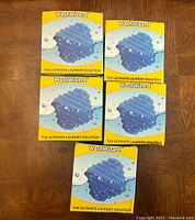 Five boxed Wash Wizard laundry solutions arranged on wooden surface, showing front packaging with product image and branding.