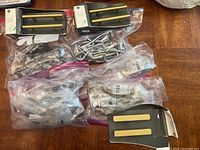 Assorted drawer pulls including gold bar pulls and other styles packed in plastic bags on table.
