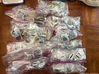 Overview photo showing all 62 drawer knobs in sealed plastic bags arranged on a surface