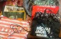Display of all eight reusable bags including Steve Madden, superhero prints, Michael Jackson bag, striped tote, and drawstring sacks