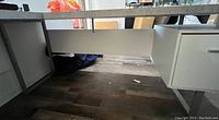 View under desk showing metal legs, bottom panel, and part of the floor beneath.