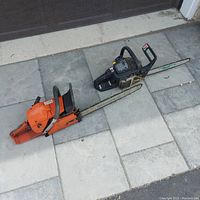 Overview of both chainsaws side by side on paving stones