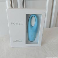 Front view of Foreo Iris eye massager in mint blue inside white retail box with clear window.