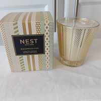 Photo of Nest New York Birchwood Pine scented candle in decorative glass and its patterned box.