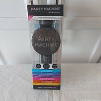 Front view of wireless microphone inside packaging. 'PARTY MACHINE' printed on speaker grille.
