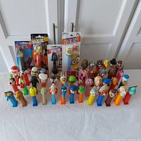 Wide view showing most of the 46 colorful Pez dispensers arranged in rows with four sealed packages at the back including Minions and Star Wars.