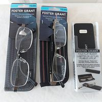 Three pairs of Foster Grant reading glasses displayed with packaging showing 2.00 magnification, two in soft cases and one fold-flat in a hard case.