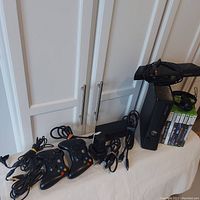 Full lot including Xbox 360 console, controllers, cables, charging station, motion sensor, headset, and 8 games.