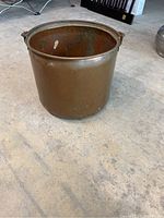 Large antique copper pot viewed from the side showing cylindrical shape and smooth exterior surface.
