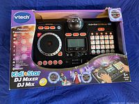 Front view of boxed Vtech Kidi Star DJ Mixer showing toy with DJ turntable, buttons, LCD, and disco ball light.