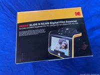 Box front showing Kodak Slide N Scan Digital Film Scanner with image of the scanner and sample photo on screen, highlighting usage for color and B&W negatives and 50 mm slides (135, 110, 126).